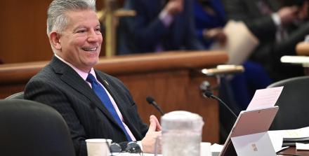 Smiling man seated alone and speaking into a microphone